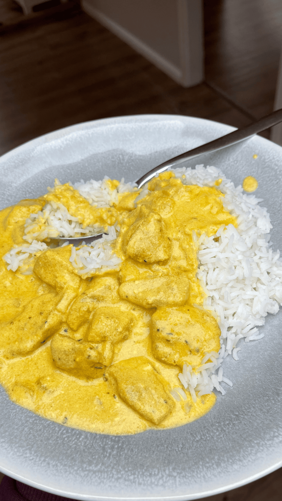 Das Bild zeigt Hähnchen geschnetzeltes in Curry Soße mit Reis.