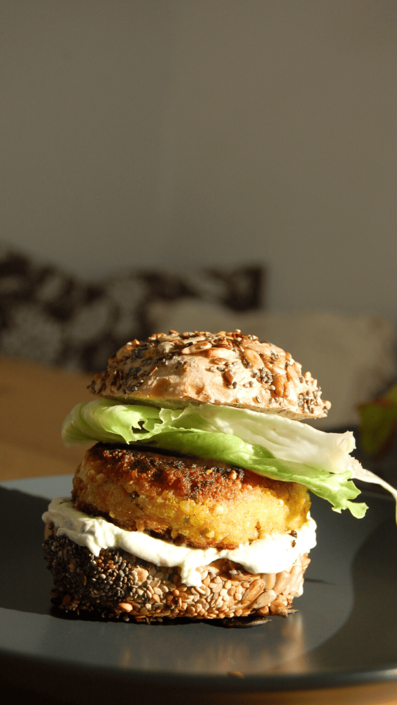 Das Bild zeigt einen selbstgemachten vegetarischen Cheeseburger mit Hirse Pattis.