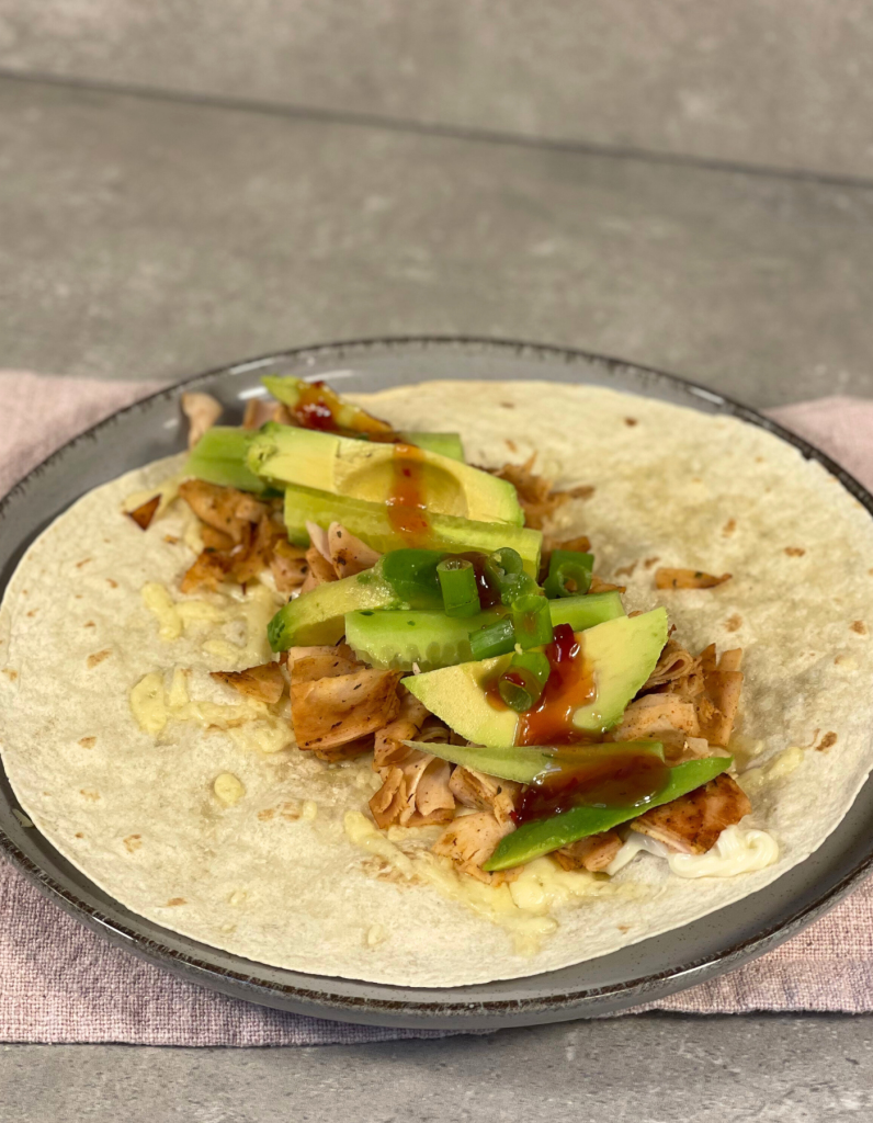 Nahaufnahme eines Wraps: Der aufgeschnittene Wrap präsentiert saftiges Hähnchen, frisches Gemüse und geschmolzenen Käse – ideal für den perfekten Biss.