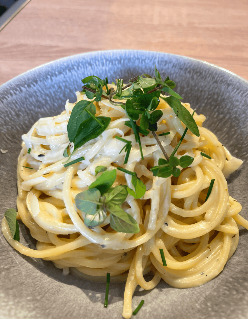 Ein Teller mit cremigen vegetarischen Spaghetti Carbonara, liebevoll mit frischen Kräutern wie Petersilie garniert.