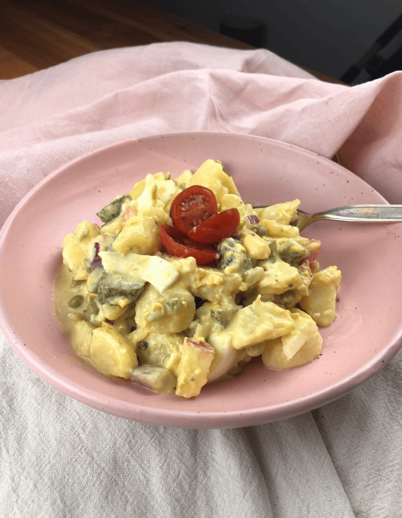 Ein großer Teller mit cremigem preußischem Kartoffelsalat, garniert mit feinen Eiwürfeln und frischen Kräutern.