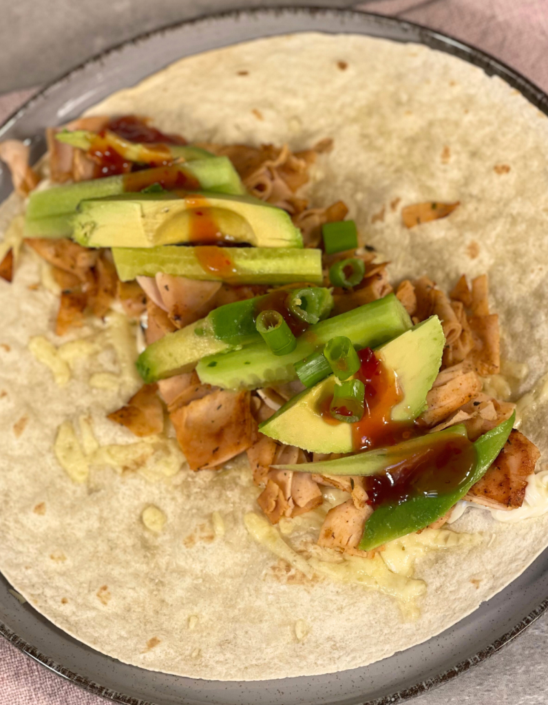 Das Bild zeigt einen Wrap mit Hähnchen und Avocado.