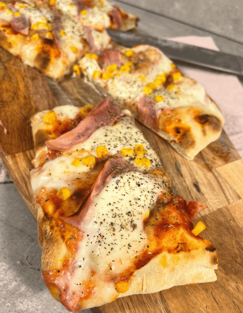 Italienische Spezialität: Eine fluffige Pinsa mit saftigem Kochschinken und cremigem, zerlaufenem Mozzarella.