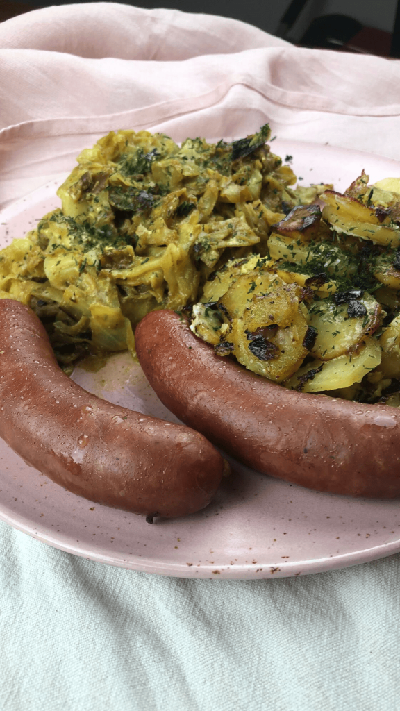 Das Bild zeigt Spitzkohl mit Bratkartoffeln und Kohlwurst.