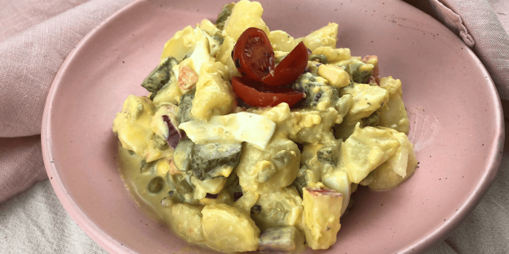 Ein rustikal angerichteter Kartoffelsalat mit cremiger Sauce, gekochten Eiern und knackigen Apfelstücken – ein klassisches, deftiges Gericht.