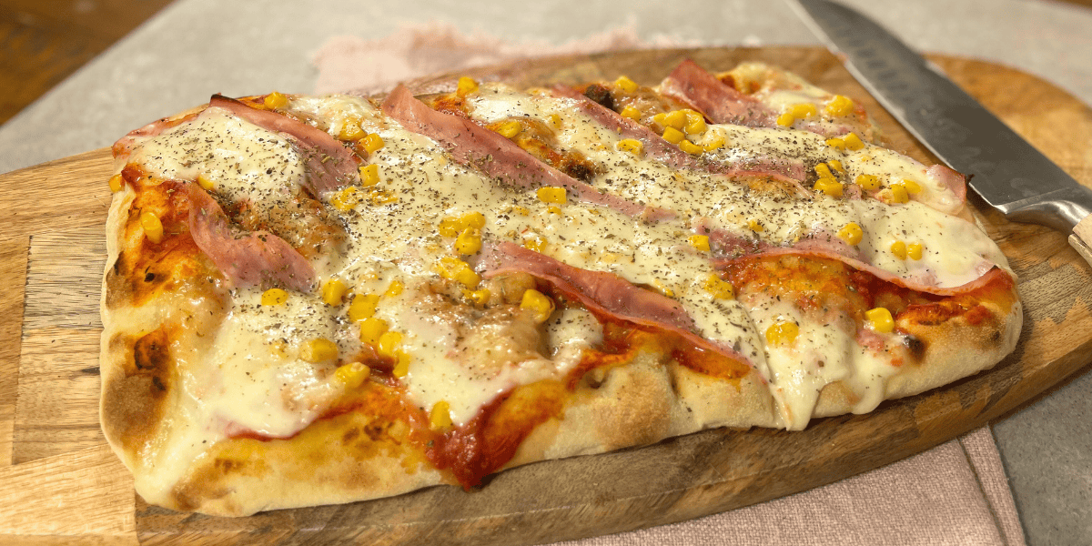 Hausgemachte Pinsa: Köstlicher Teigfladen, belegt mit feinem Kochschinken und einer goldenen Schicht Mozzarella.
