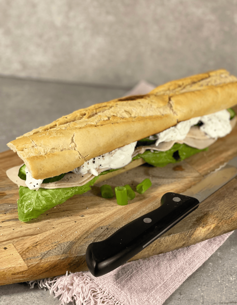 Ein knuspriges Baguette auf einem rustikalen Holzbrett, aus dem cremiger Burrata verführerisch herunterläuft.