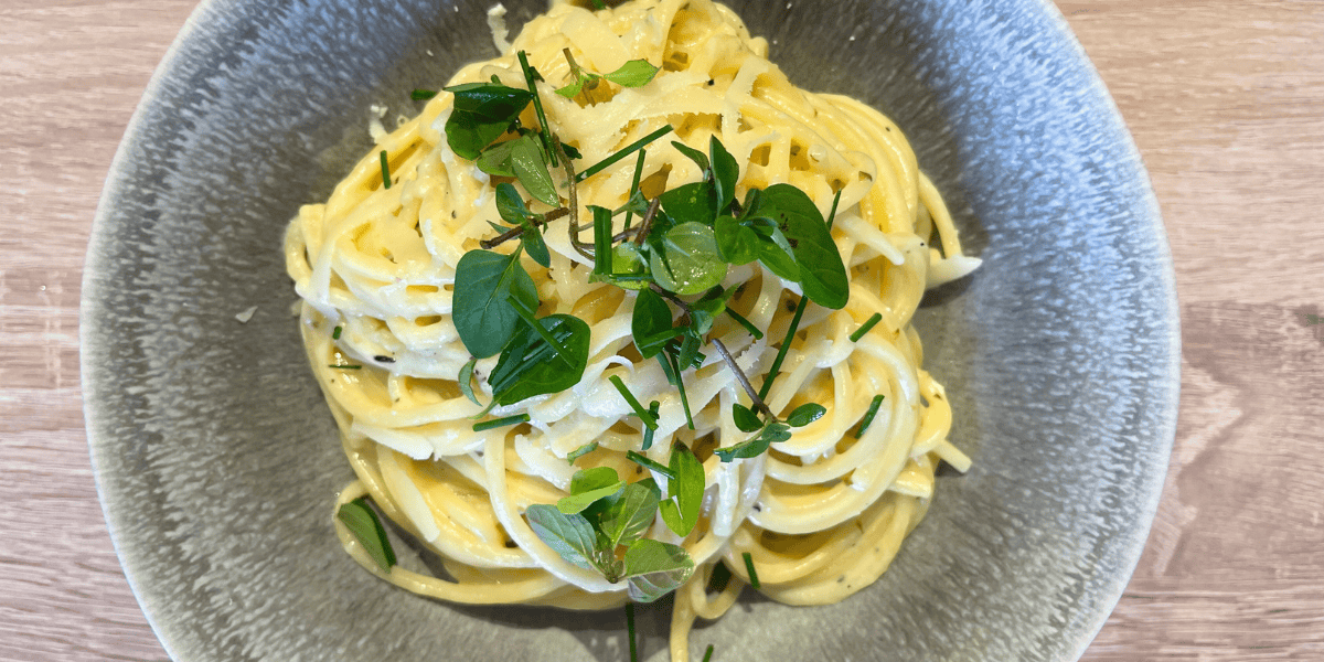 Goldgelbe Spaghetti Carbonara, verfeinert mit frischen Kräutern und einem Hauch geriebenem Grana Padano.