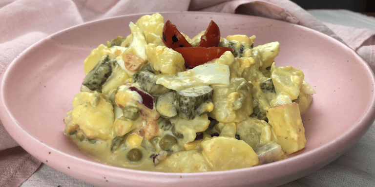 Der fertige preußische Kartoffelsalat: Würzige Kartoffelwürfel mit Mayo-Dressing, frischen Zwiebeln und buntem Gemüse, appetitlich serviert.