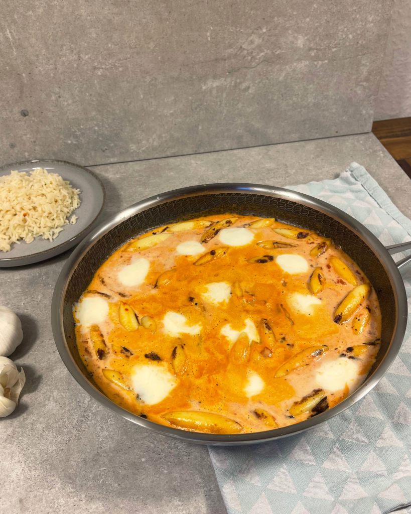 Eine goldbraun gebratene Schupfnudelpfanne mit cremiger Sahnesoße, garniert mit geschmolzenen Mozzarellakugeln.