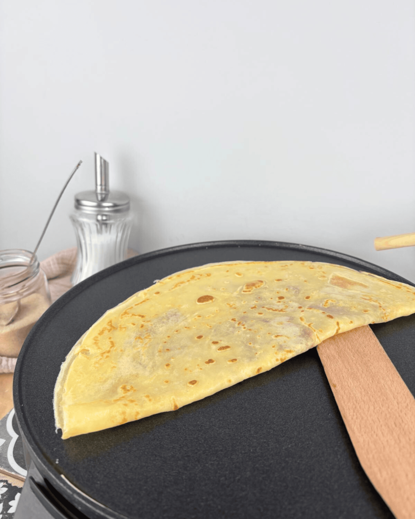 Das Bild zeigt einen frisch gebackenen Crepe, der auf einem Crepesmaker liegt, perfekt goldbraun gebacken und bereit zum Servieren.