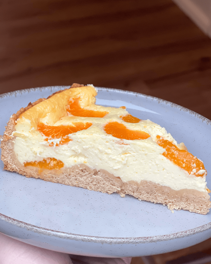 Ein Stück vom Mandarinen Käsekuchen wo man die helle Quarkfüllung sieht.