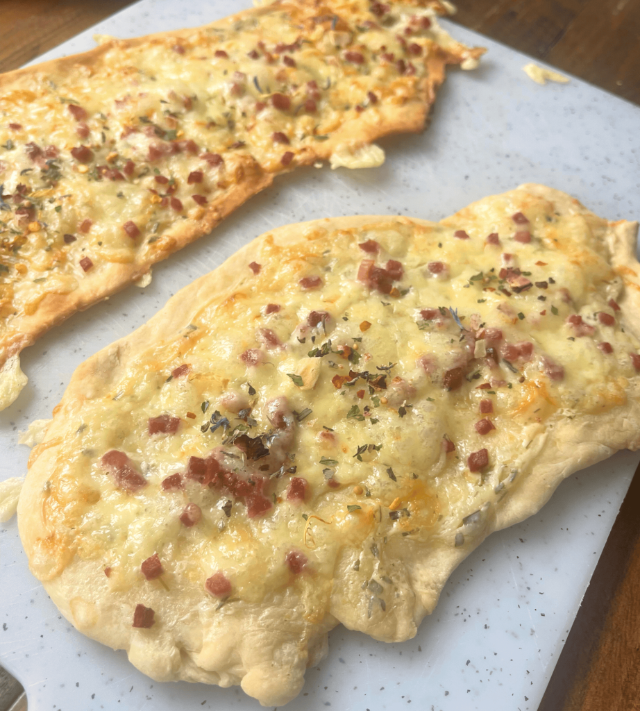 Das Bild zeigt einen leckeren frisch gebackenen Flammkuchen. 