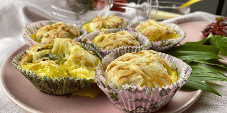 Knusprig-herzhafte Käsemuffins, serviert auf einem rosafarbenen Teller, mit goldbraunem Käse überbacken.